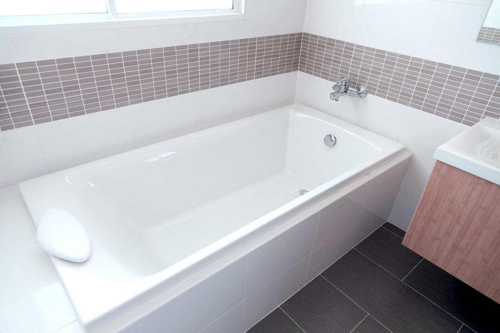 A clean white bathtub in an updated bathroom.