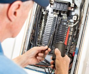 Technician inspects electrical panel.