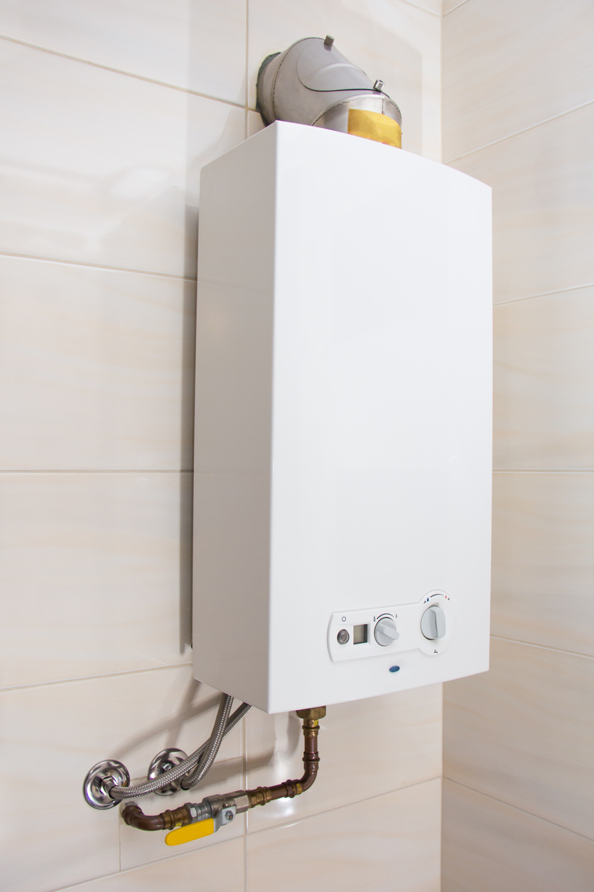 Tankless water heater installed on a white tile wall.