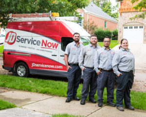 Four JD Service Now technicians stand in a row, in front of a service truck.