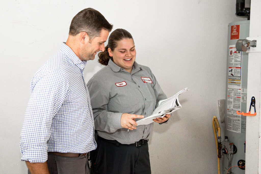 JD Service Now plumber talks to homeowner while standing in front of a water heater