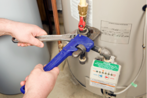 person repairing a water heater with a purple wrench