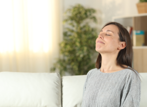 woman breathing in deeply through nose in living room, clean air no allergens