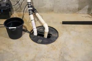 Sump pump system with PVC discharge pipes installed in a basement floor pit.