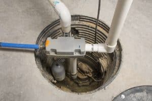 Sump pump installed in a basement pit with PVC plumbing and a float switch.